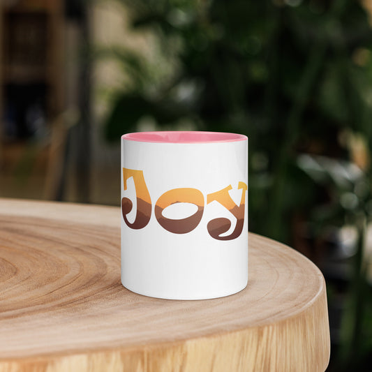 White Ceramic Mug with Pink Coloured rim, inside, and handle with the Word Joy inlaid with Sun image on Table 